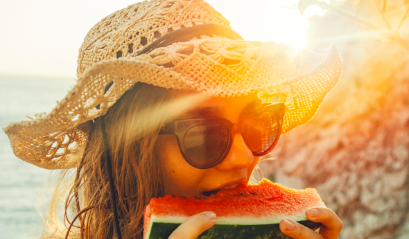 BBGR, femme avec un chapeau, portant des lunettes équipées de verres solaire et mangeant une part de past&egrave;que, en &eacute;t&eacute;.